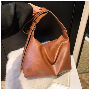 Detailed close-up of brown faux leather hobo bag with adjustable strap and silver buckle