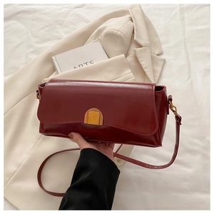 Detail of dark red leather shoulder bag featuring a vintage gold semicircular buckle