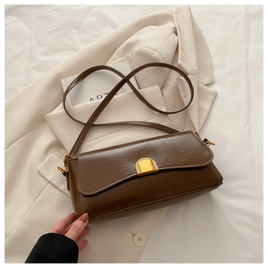 Detail of dark brown vintage baguette bag with glossy leather and gold metal buckle