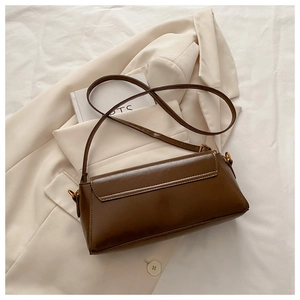 Brown retro leather underarm bag with gold hardware placed on a beige blazer