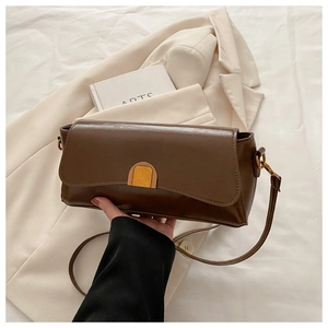 Detail of dark brown leather underarm bag with gold semicircular buckle and slim strap