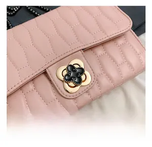 Close-up of quilted light pink leather bag featuring a gold floral hardware clasp detail
