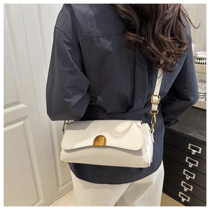Close-up of white textured shoulder bag with golden metallic buckle worn by a model