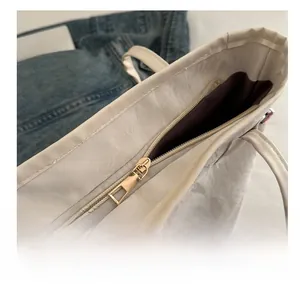 Détail de la fermeture éclair en métal doré sur le sac fourre-tout en cuir beige texturé