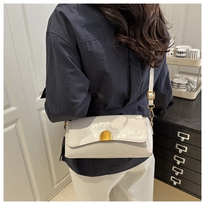 Detail of white glossy leather handbag featuring elegant gold metal clasp and soft texture