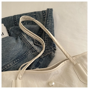 Detail of white tote bag featuring natural pleated texture and elegant pearl decoration