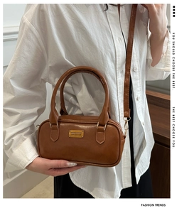 Detail of a brown vintage cylinder bag featuring golden hardware and double handles