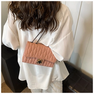 Détail d'un sac à bandoulière matelassé rose-orange avec fermoir doré et chaîne en métal