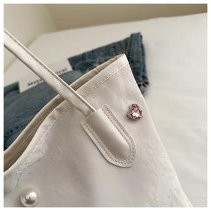 Detailed close-up of white marble textured tote bag with pink heart crystal and pearl