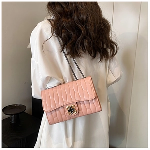 Pink quilted leather crossbody bag with floral metal clasp and grey chain strap worn by model