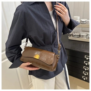 Detail of vintage brown pleated leather bag featuring a gold semi-circular metal clasp