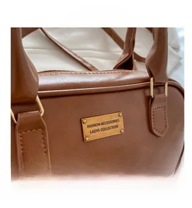 Detailed close-up of brown vintage Boston bag featuring a metallic fashion engraved plate