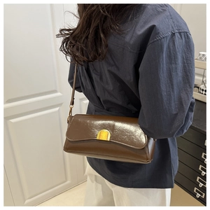 Détail du sac sous le bras en cuir brillant marron foncé vintage avec boucle dorée