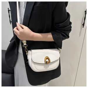 Close-up of white leather saddle bag with gold horseshoe buckle on black blazer