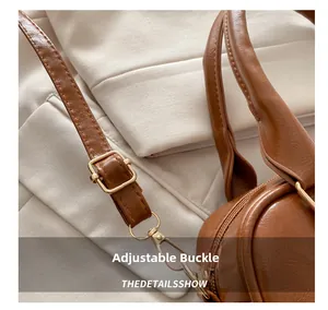 Detail of adjustable buckle and gold lobster clasp on brown leather shoulder bag