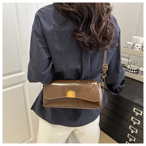 Gros plan du sac à bandoulière marron foncé avec boucle dorée élégante en demi-cercle