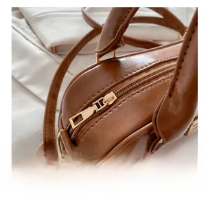 Detailed close-up of the smooth golden zipper and refined stitching on the brown leather bag