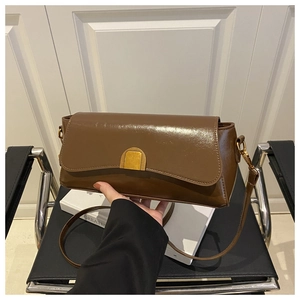 Detail of vintage brown glossy leather bag with gold rectangular clasp and slim shoulder strap