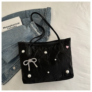 Detail of black tote bag with white pearls, silver rhinestone bow and pink heart charm