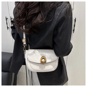 Detail of white vintage flap bag featuring a polished gold horseshoe turn-lock buckle