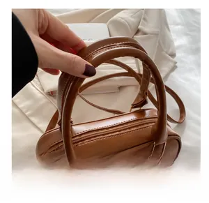 Close-up of brown textured leather pillow bag with round handles and metal zipper