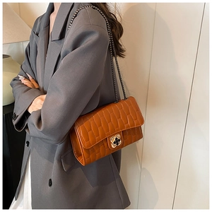 Détail du sac bandoulière matelassé caramel avec fermoir floral doré et chaîne