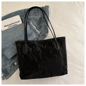 Detailed view of black tote bag with unique crinkled texture and sleek shoulder straps