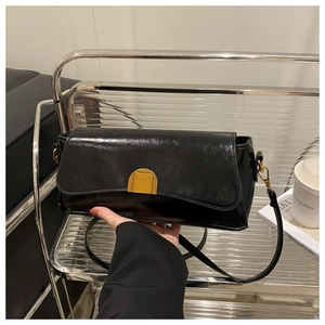 Close-up of black glossy faux leather shoulder bag with gold half-moon metal buckle