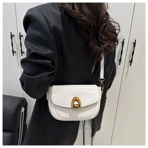 Detail showing white saddle bag with vintage gold horseshoe buckle on a black blazer