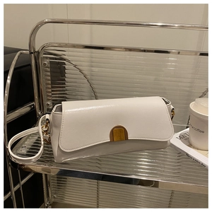 Detail of a white crossbody bag featuring a vintage gold clasp on a metallic rack