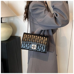 Détail du sac matelassé noir avec fermoir fleuri doré et bandoulière en chaîne