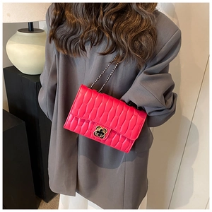 Détail du sac à bandoulière texturé rose vif avec fermoir trèfle et chaîne métallique