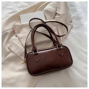Detail of dark brown retro crossbody bag featuring smooth finish and metal buckle strap