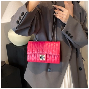 Détail du sac bandoulière matelassé rose rouge avec fermoir fleur dorée et chaîne