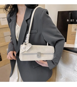 Detail of elegant beige crossbody bag with silk scarf strap and sparkling buckle