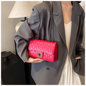 Détail du sac bandoulière matelassé rouge rose avec fermoir floral et chaîne en métal