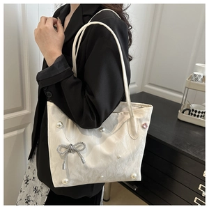 Detail of white tote bag with pearl accents and a silver rhinestone butterfly bow