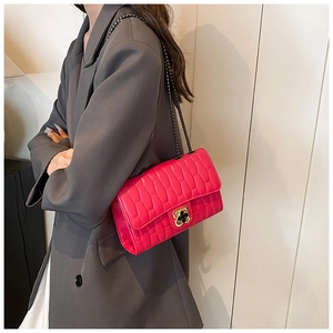 Détail du sac à chaîne matelassé rose avec boucle trèfle sur un blazer gris chic