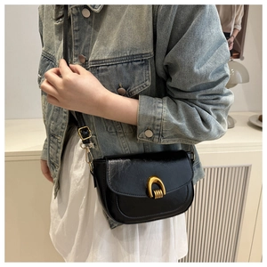 Detail of vintage black saddle bag with elegant gold U-shaped metal buckle on the flap