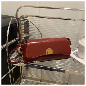 Detail view of burgundy leather handbag with asymmetric flap and golden hardware