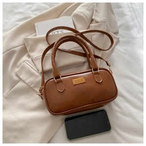 Detail of caramel brown PU leather crossbody bag with dual handles and gold metal logo