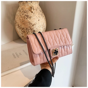 Gros plan détaillé d'un sac bandoulière rose matelassé avec fermoir trèfle doré