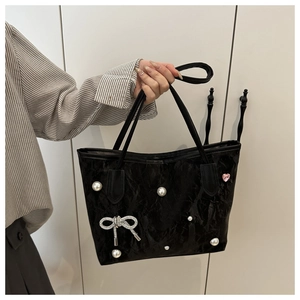 Detail of black tote bag featuring elegant pearls and a sparkling diamond bow charm