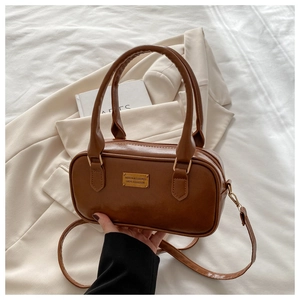 Detailed close-up of dark brown bowling bag with gold metal plate and textured leather