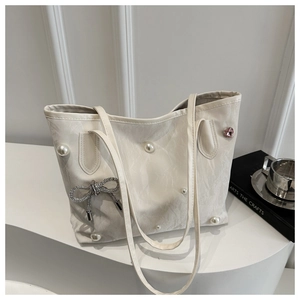 Detail of off-white pleated tote bag with pearls, diamond bow, and heart charm