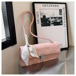 Close-up of pink suede shoulder bag with decorative silk scarf and silver metal clasp