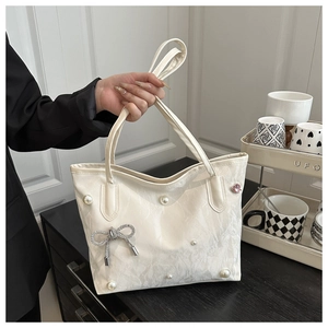 White tote bag with pearl accents, silver diamond bow, and pink heart charms detail