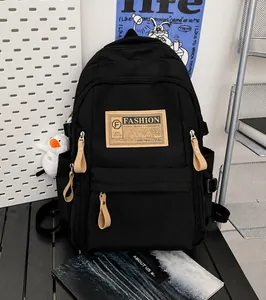 Detail of black nylon backpack featuring khaki zipper pulls and a fashion label