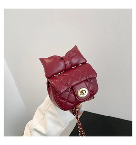 Close-up of wine red quilted crossbody bag featuring a large bow and gold twist lock