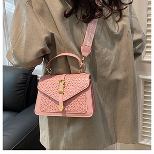 Pink woven leather crossbody bag with gold buckle and stylish patterned shoulder strap